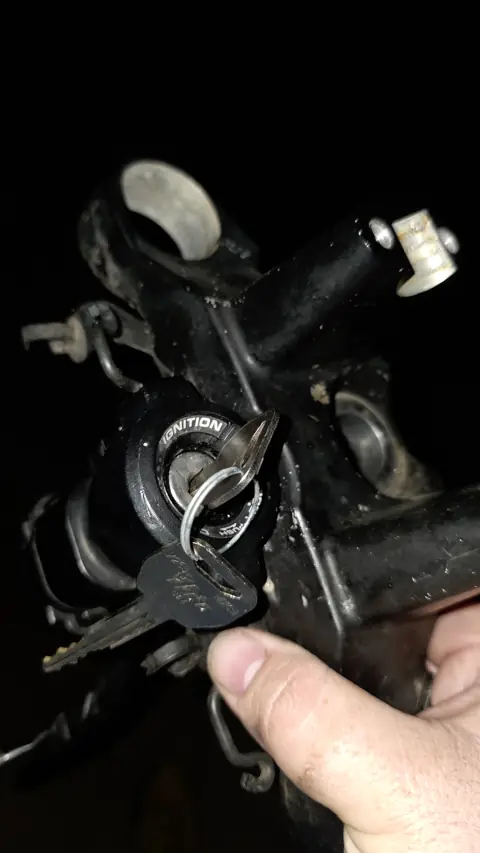 Motorcycle ignition switch being replaced at night with a new key